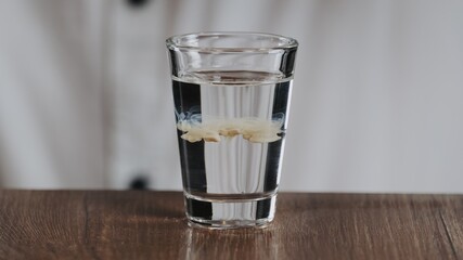 The bartender drips a drop of irish cream from a drinking straw to glass with sambuca