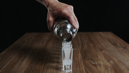 Bartender pouring kamikaze alcochol cocktail from a shaker to glasses