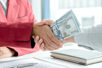photo of Businessmen shake hands and dollar note, sign a contract to bribe corruption in the company. The concept of bribery and corruption
