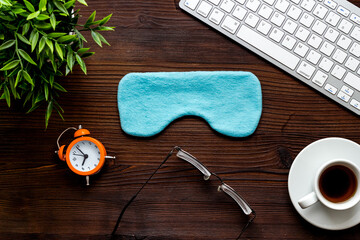 Flat lay of sleep mask on wooden office desk from above