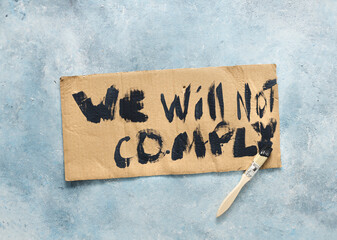Protests concept. Phrase we will not comply written on cardboard top view