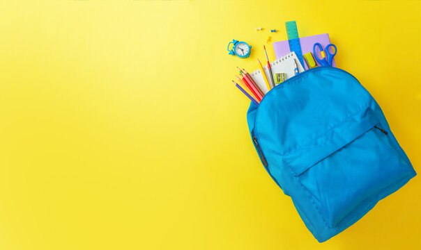 School bag. Backpack with supplies for school on yellow background. Copy space for text