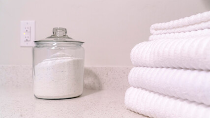 Obraz na płótnie Canvas Panorama crop Folded white towels and glass jar with white powder on the bathroom countertop