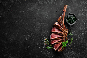 Sliced Tomahawk Steak on the bone with spices and herbs. Top view. Free copy space.