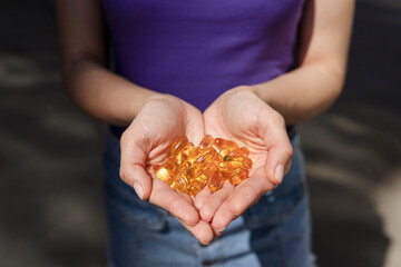 A handful of vitamin d capsules are in women's hands. Blurred background