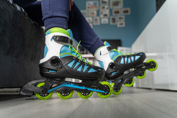 Close up on feet of unknown woman sitting on the sofa bed at home with roller blades inline skates...