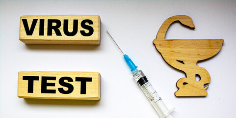 Words virus test on white background with vaccine and wooden medicine sign.