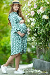 Naklejka premium Pregnant woman in nature. Beautiful woman holds belly.