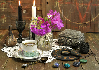 Still life with zodiac chart, black candle, cup and stones.
