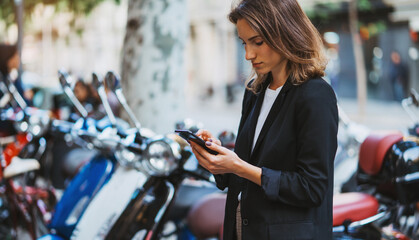 elegant girl standing at parking mopeds on street city using  smart phone online app rents fast...