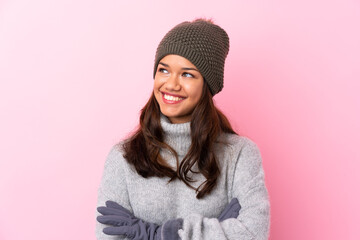 Young Colombian girl with winter hat over isolated pink wall looking to the side