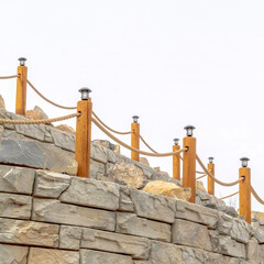 Naklejka premium Square frame Rope fence with lamps on posts lining a retaining wall made of stone blocks