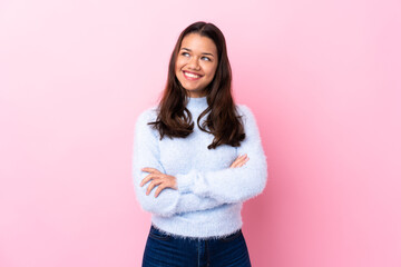 Young Colombian girl over isolated pink background looking to the side