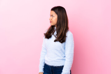 Young Colombian girl over isolated pink background looking side