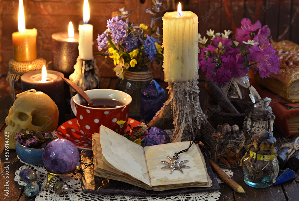 Wall mural Still life with cup of tea, burning candles, open diary with copy space and crystal on witch table.