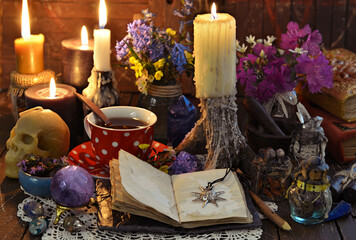 Still life with cup of tea, burning candles, open diary with copy space and crystal on witch table.