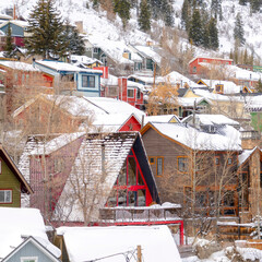 Fototapeta na wymiar Square frame Stunning winter neighborhood with colorful houses nestled on snow covered hill