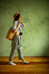 Tourist in a denim jacket and hat with a camera and bag. Happy emotions