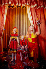 Family with dog during stylized theatrical circus photo shoot in beautiful red location. Model...
