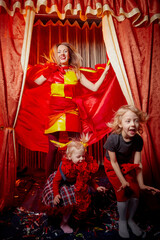 Family with dog during stylized theatrical circus photo shoot in beautiful red location. Model...