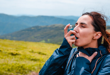 Woman hiker taking asthma pump inhalation.