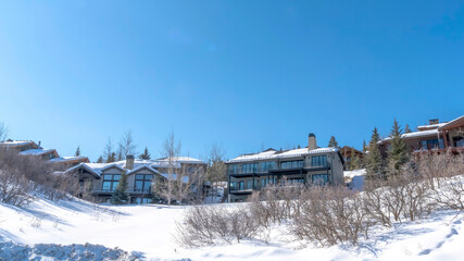 Fototapeta na wymiar Panorama Houses on snowy hill terrain in Park City Utah with clear blue sky background