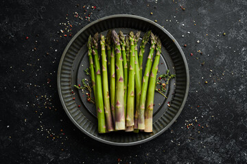 Fresh green asparagus on a black stone background. Healthy food. Top view, free copy space.