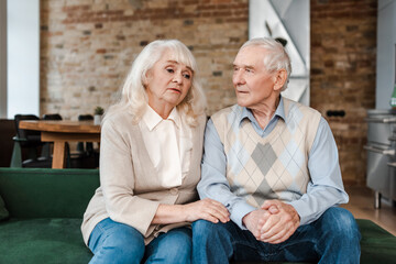 upset senior couple sitting at home on self isolation