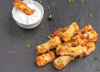 Zucchini baked with parmesan cheese and herbs on a black background. Appetizing zucchini in the form of sticks. Vegetarian cuisine. Vegetable course.