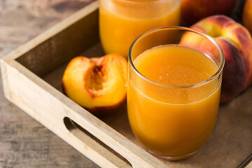Natural peach juice in glass on wooden table	