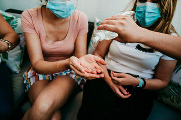 Obraz na płótnie Canvas .Group of young girlfriends meeting after the quarantine caused by the covid pandemic19. Taking precaution with the use of surgical masks and cleaning your hands with hydroalcoholic gel. New normal