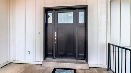 Panorama Black wooden front door with glass panes against panelled exterior wall of home