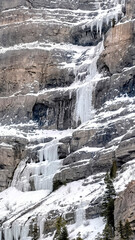 Fototapeta na wymiar Vertical crop Bridal Veil Falls with frozen water on steep slope during winter in Provo Canyon