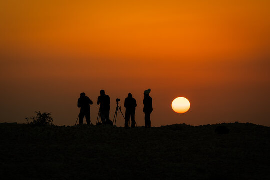 Silhouette of a group of photographers taking a sunrise picture from a mountain in Bahrain
