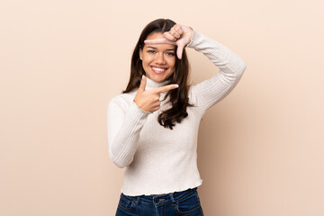 Young Colombian girl over isolated background focusing face. Framing symbol