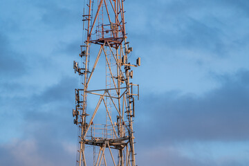 5g 6g mobile communications tower standing on the street against a background of blue clouds