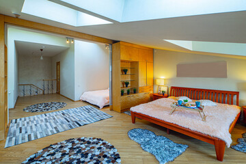 Modern interior of bedroomwith two beds in apartment. Roof windows. Zoning with sliding door. Wooden furniture.