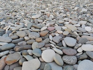 Perspective of rounded sea pebble stones & rock on beach natural abstract pebble texture background. Small multicolor river pebble rock stones. Close up colorful rock stones or gravel on ocean coast.