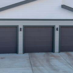 Square frame Three door garage of a lovely home against snowy slope and cloudy blue sky