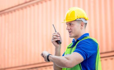 Engineer man in hardhat and safety vest talks on two-way radio, Worker man looking at the watch time at containers cargo