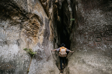 A young male amateur speleologist enters a mountain cave with a backpack