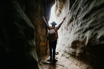 A male traveler comes out of the cave and rejoices with his hands up. The concept of success
