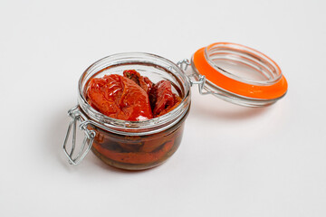 Homemade organic sauce with dried tomatoes, olive oil and spices in a glass jar on a white background, isolate, close up