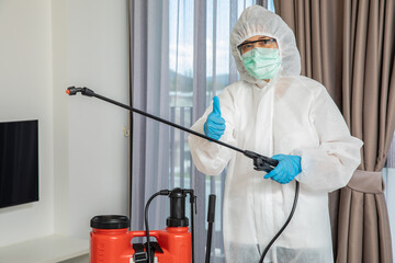 Professional cleaning staff with a To wear protective medical mask and PPE suit use chemical sprayer protect decontamination home 