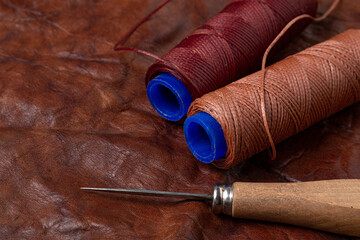 Spools of threads on a leather background. Leather workshop