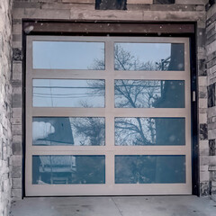 Square Close up of glass panel garage door of home with stonw brick exterior wall