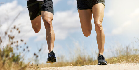 Young fit couple legs running around field under sunlight