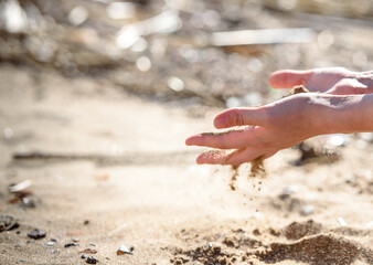 Hand is pouring coral sand on a beach