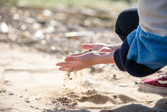 Hand is pouring coral sand on a beach