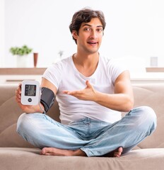 Young man measuring blood pressure at home